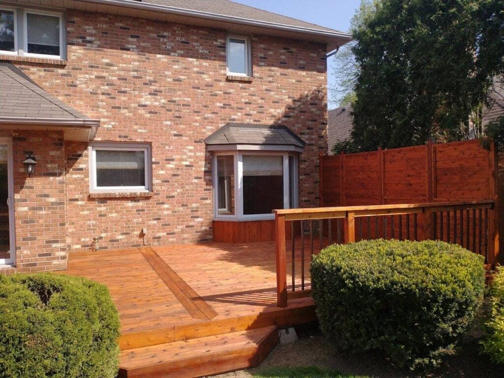 Cedar deck and railing stained beside a brick home