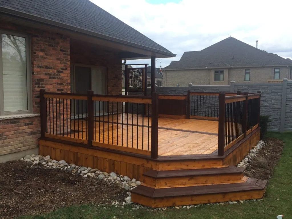 A homeowner sweeping debris off a stained deck in a Kitchener-Waterloo backyard during early fall