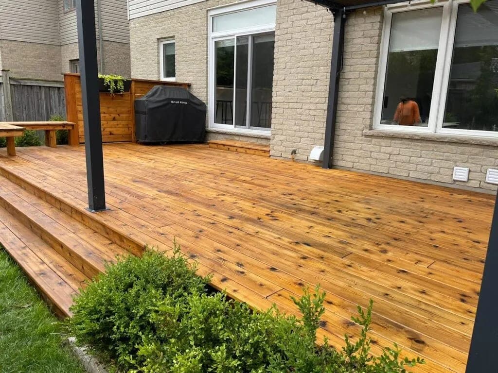Refinished deck in a honey-toned stain beside a brick bungalow