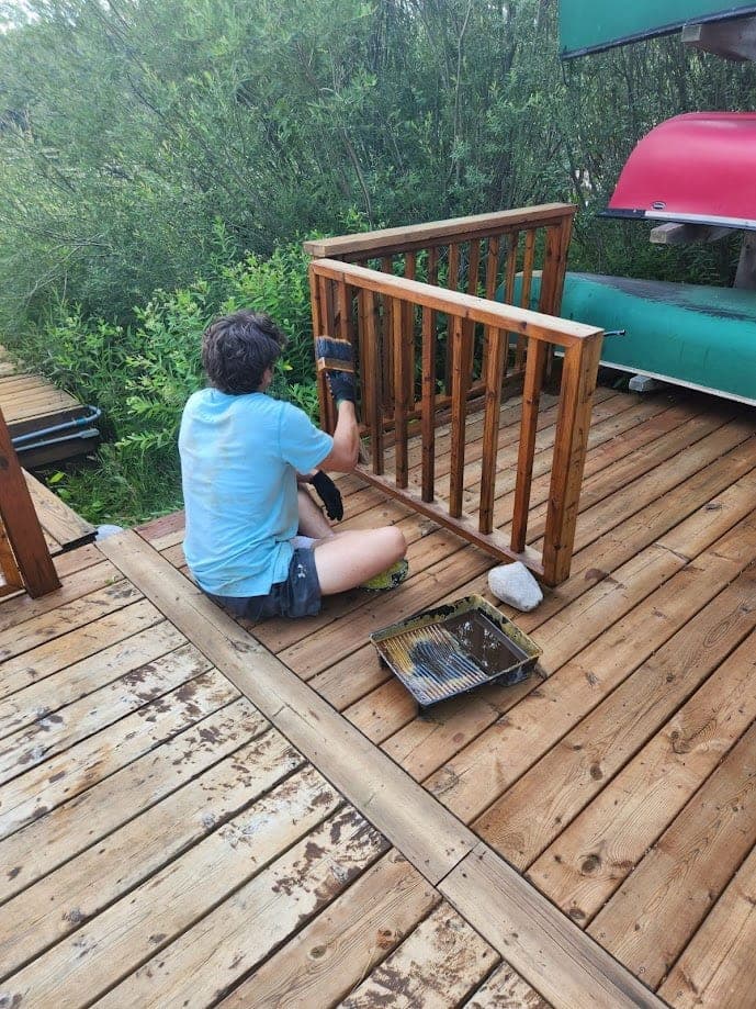 Restore My Deck technician hand-sanding a deck railing before staining